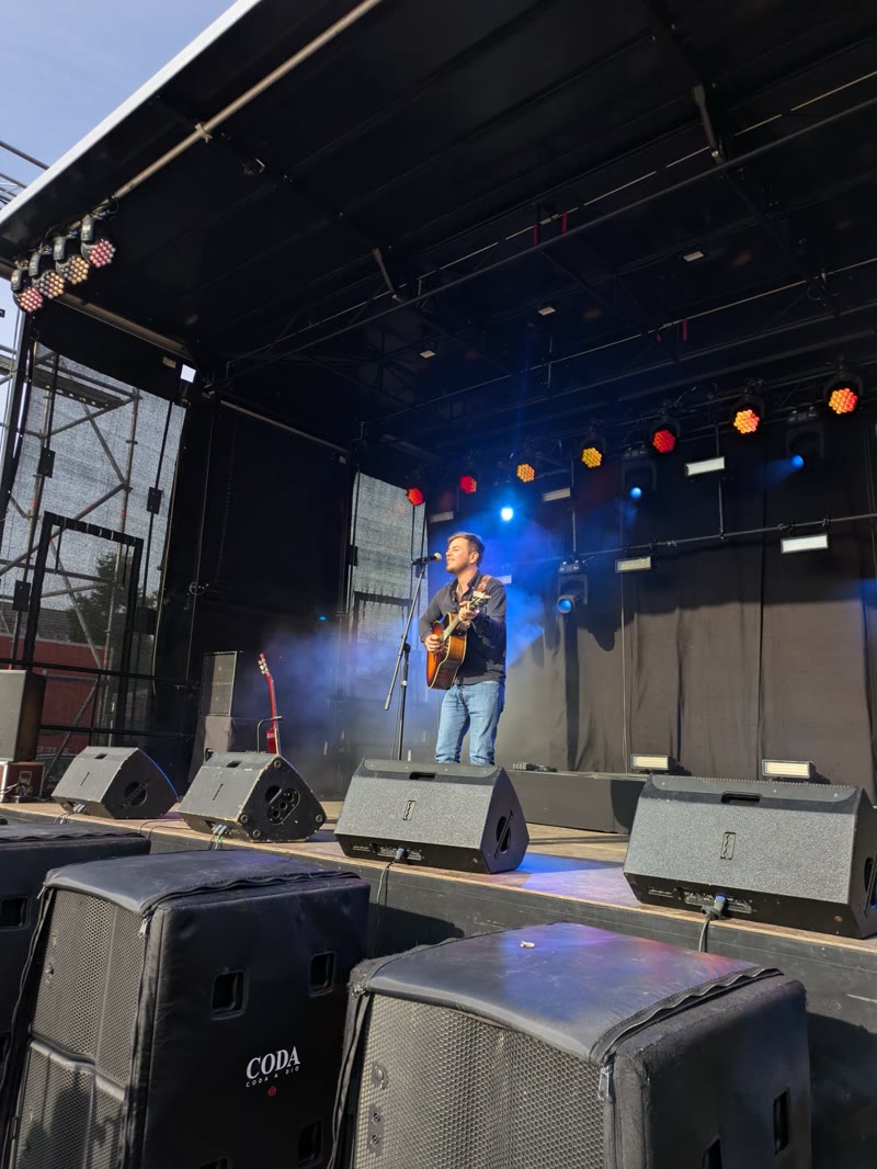 GuitarJoe performing solo fingerstyle guitar on a market square
